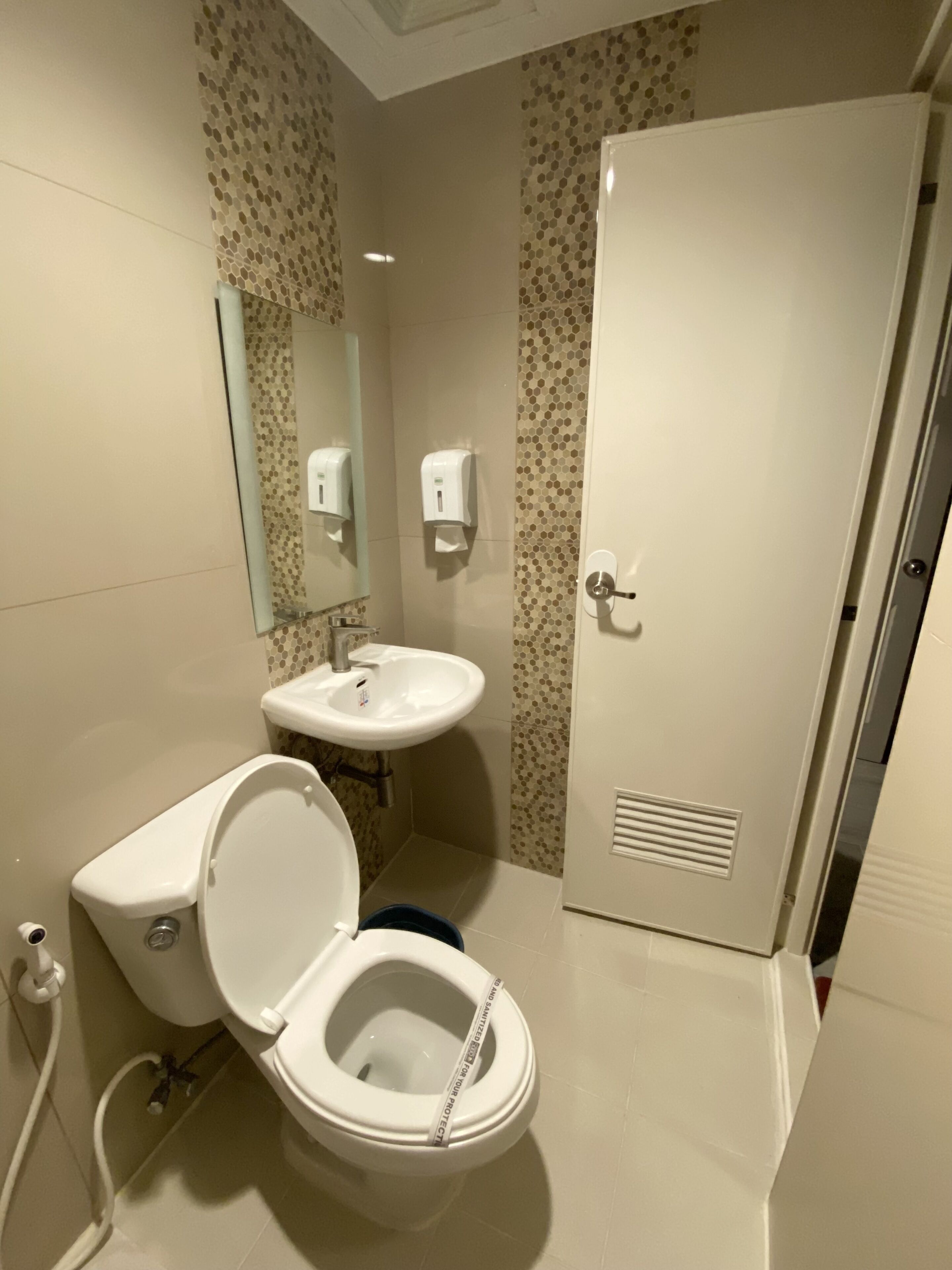 A bathroom with a toilet, sink, and mirror.
