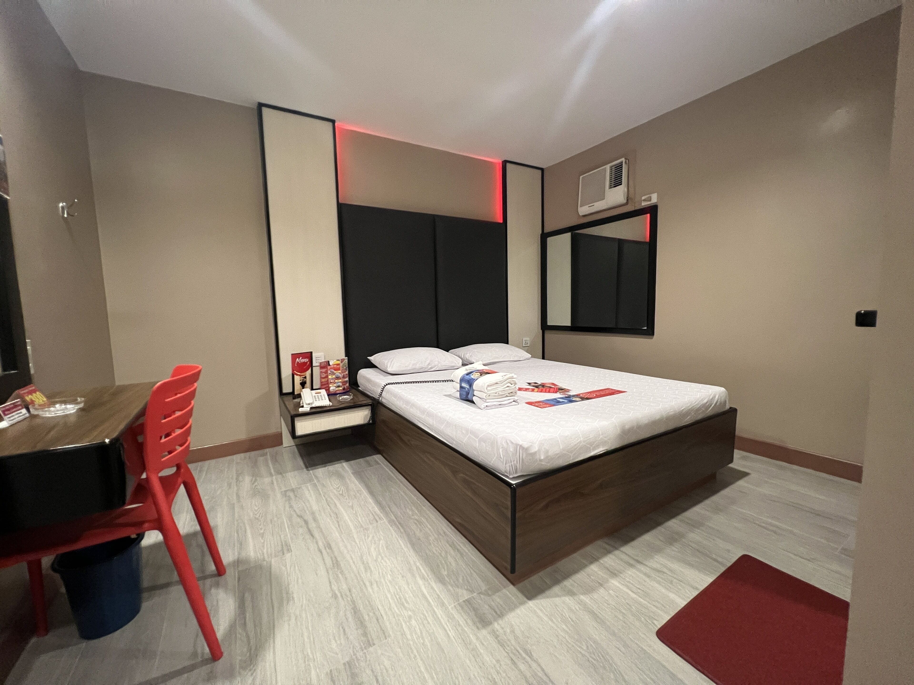 A modern hotel room with a bed, a desk, and a chair.
