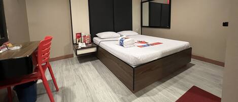 A modern hotel room with a bed, a desk, and a chair.