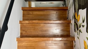 Eine Holztreppe mit schwarzer Handlauf und einer Wand mit einem Blumenmuster.