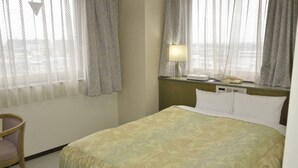 Une chambre d’hôtel avec un lit, une chaise, une table de chevet avec une lampe et un téléphone.