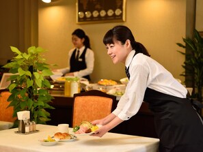 A dining area with a table set for a meal, a plant, and a clock on the wall. - Pulses Inn Kyoto (Kyoto)