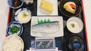 Un plateau contenant divers plats japonais, notamment du riz, du poisson et des légumes marinés.