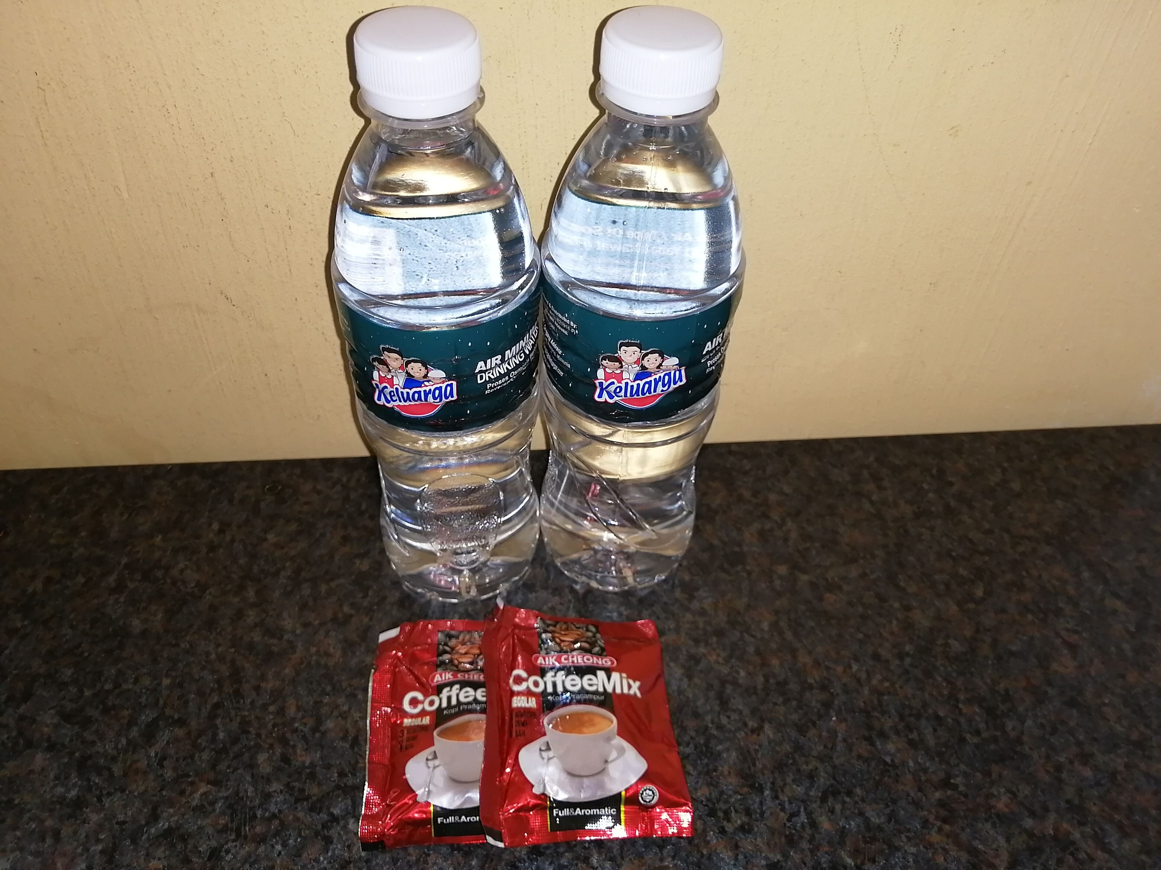 Twee waterflesjes en twee zakjes koffiemelk op een aanrecht.