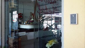 A hotel entrance with a glass door, a 'PULL' sign, and a security keypad on the wall. - Rasa Motel (George Town)