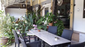 An outdoor patio with a table and chairs, surrounded by potted plants and a building with a sign that reads "Motel". - Rasa Motel (George Town)