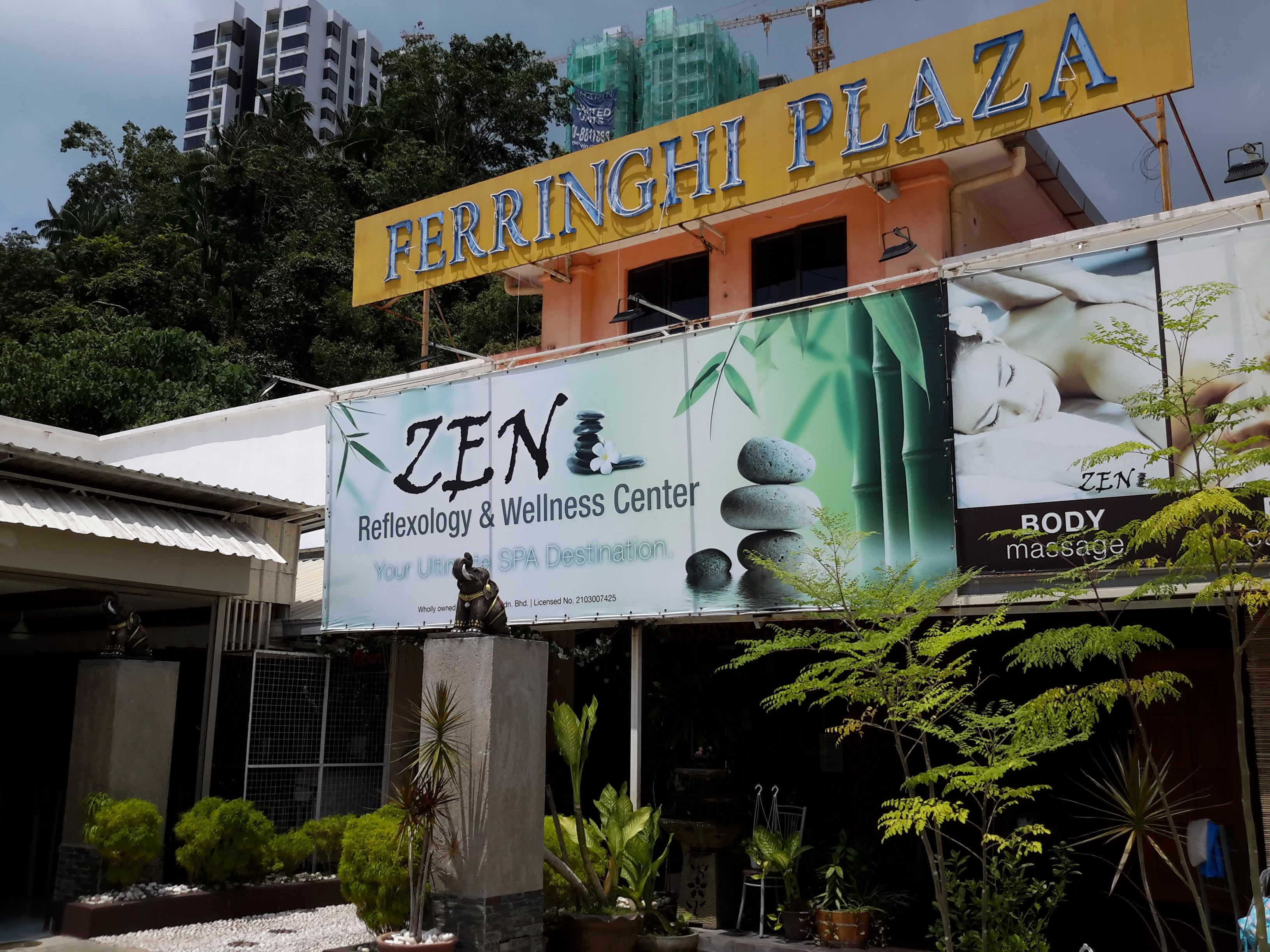 A building with a sign for 'FERRINGHI PLAZA' and a large 'ZEN' sign advertising a Reflexology & Wellness Center.