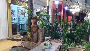 An indoor seating area with a table and chairs, surrounded by potted plants. - Rasa Motel (George Town)