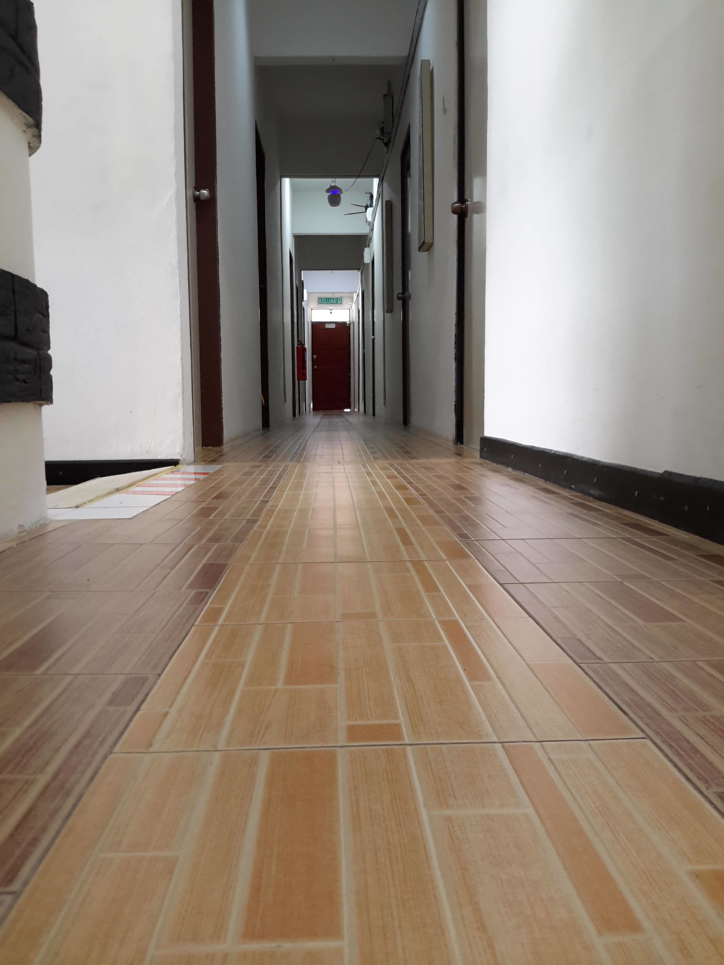 En lång, smal hall med kakelgolv och vita väggar.