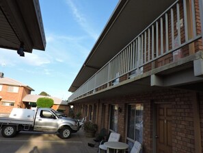 A building with a brick facade, a balcony with white railings, and a parked truck.