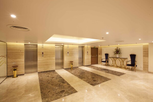 A modern lobby with elevators, a reception desk, and seating area. - United-21 The Grand (Pune)