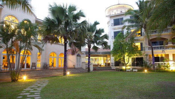 A hotel courtyard with palm trees, a stone pathway, and a well-lit entrance. - Formosa Garden Hotel (Tainan)
