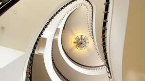 A multi-level spiral staircase with a central light fixture and a view of the outdoors through a window. - Formosa Garden Hotel (Tainan)