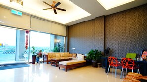 A modern lobby with a sofa set, red chairs, and a ceiling fan. - Kenting Green Yard B&B (Hengchun)