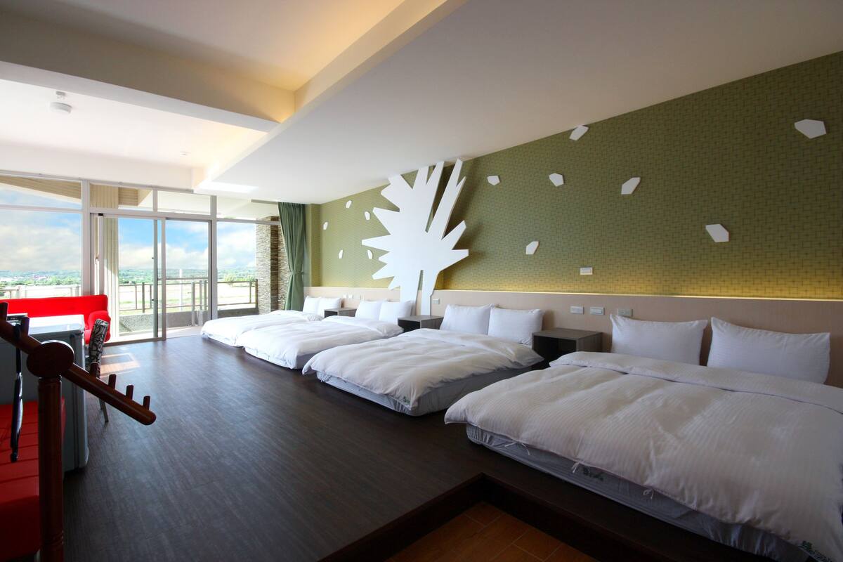 A hotel room with two beds, a balcony, and a view of the city.