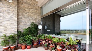A balcony with potted plants and a clock. - Kenting Green Yard B&B (Hengchun)