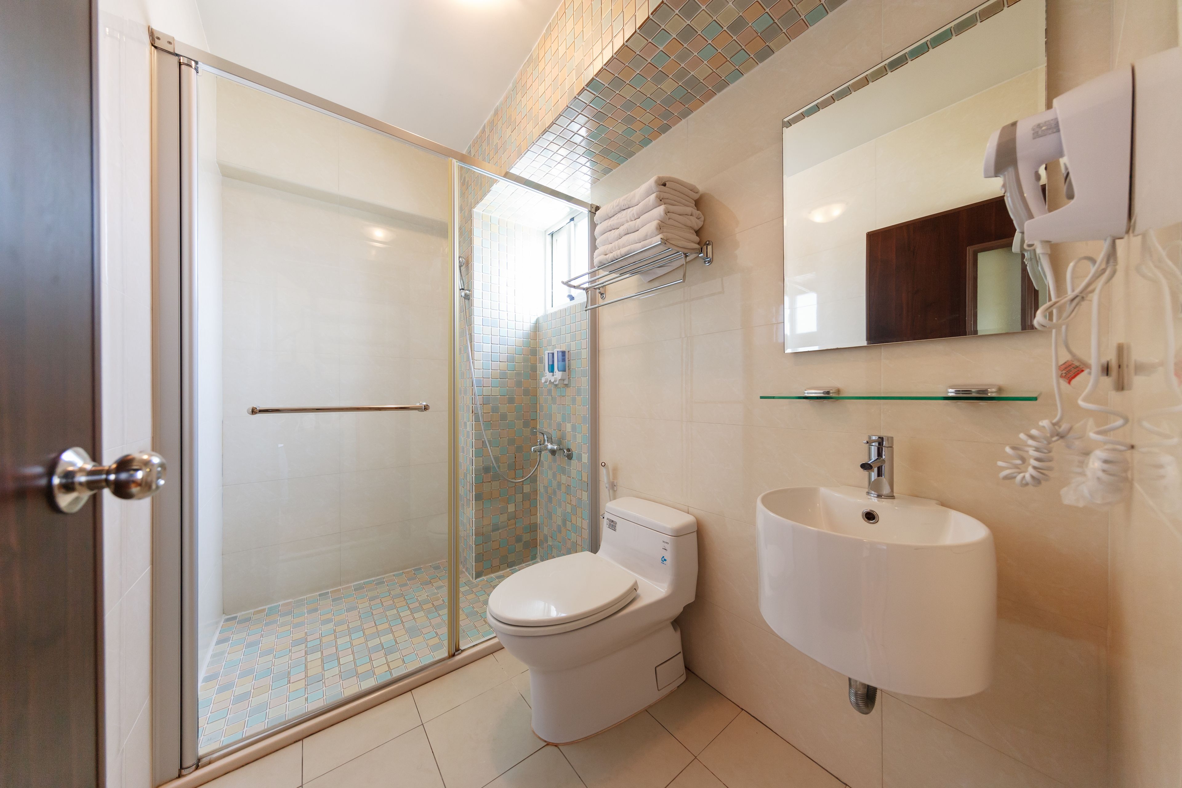 A modern bathroom with a glass-enclosed shower, a toilet, a sink, and a towel rack.