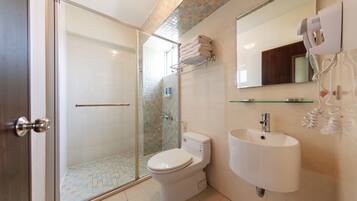 A modern bathroom with a glass-enclosed shower, a toilet, a sink, and a towel rack.