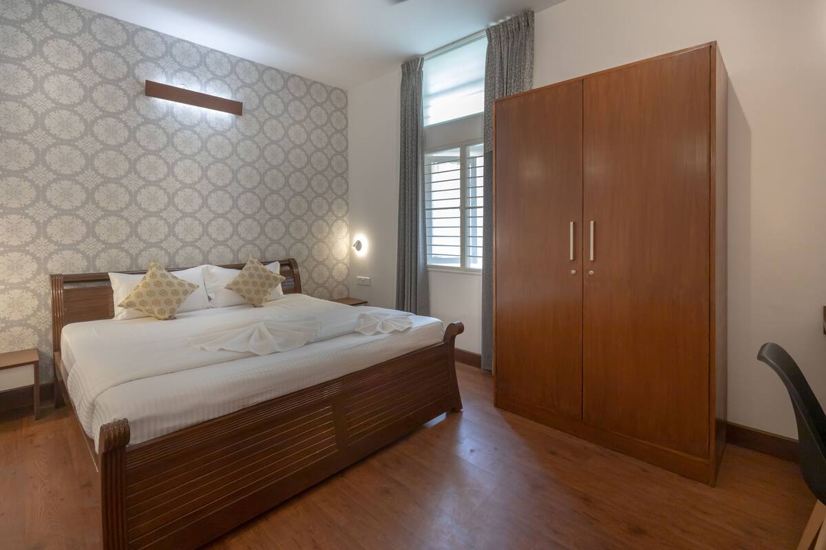 Un dormitorio con una cama de madera, un armario, una mesita de noche y un papel tapiz estampado.