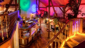 A multi-level bar area with wooden railings, a staircase, and a variety of seating arrangements.