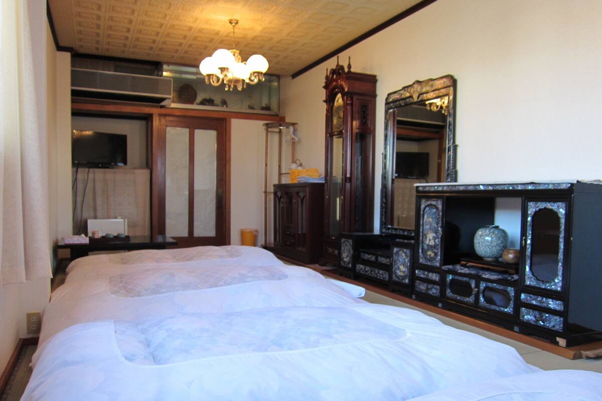 Ein Schlafzimmer mit einem großen Bett, einem Holzschrank, einem Spiegel und einer Pendelleuchte.