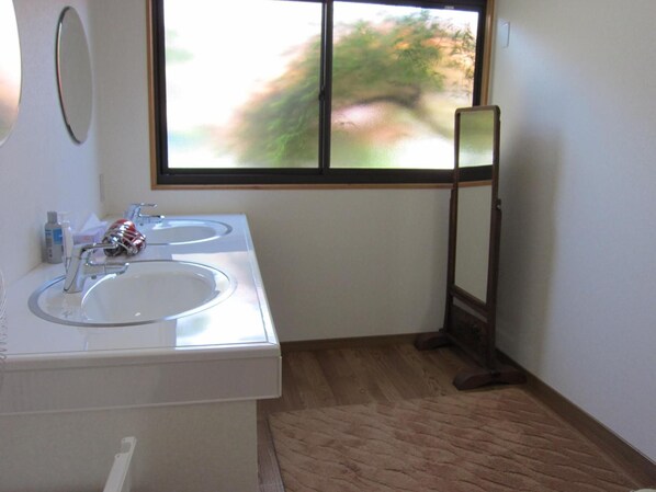 A bathroom with two sinks, a mirror, and a window with a view of trees. - Ryokan Matsukaze (Matsumoto)