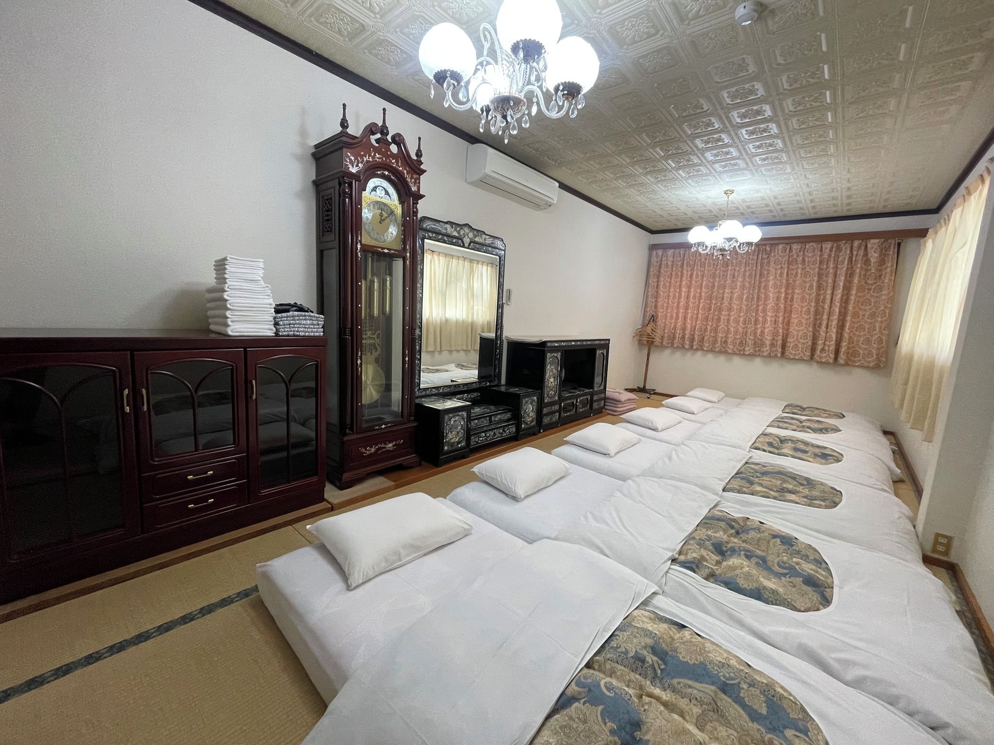 Una habitación con una cama grande, un armario de madera, un espejo y una araña.