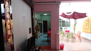 A hotel room with a TV, a desk, and a chair. There is a balcony with a red umbrella and a table with chairs. - Backpackers@SG - Hostel (Singapore)