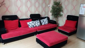 A modern living room with a black and red sofa set, a small table, and a potted plant. - Backpackers@SG - Hostel (Singapore)