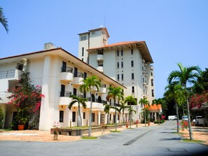 Ein mehrstöckiges Hotel mit Balkonen, Palmen und blauem Himmel.