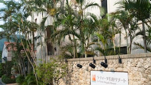 Une enseigne pour le complexe hôtelier La Teida Ishigaki, avec un mur en pierre et des plantes tropicales.
