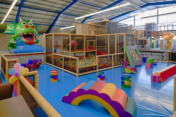Un espace de jeux doté de diverses structures ludiques, notamment une piscine à balles, des toboggans et un mur d’escalade.