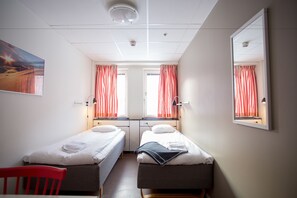 A twin room with two single beds, a red chair, and a large mirror on the wall. - STF Gärdet Hotel & Hostel (Stockholm)
