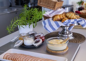 A breakfast setup with croissants, sliced apples, and various spreads on a table. - STF Gärdet Hotel & Hostel (Stockholm)