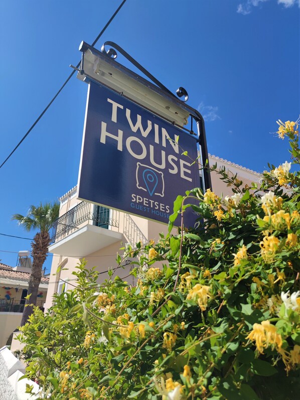 A sign for 'Twin House' with a location pin icon, indicating a guest house or lodging option.