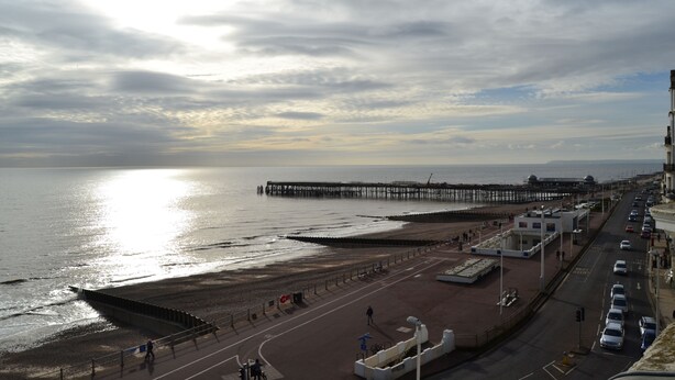 A coastal road with a beach and a pier in the background. - The Lindum (Hastings)