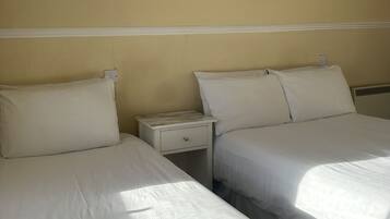 Una habitación de hotel con dos camas, una mesita de noche, una lámpara de pared y un cuadro enmarcado.