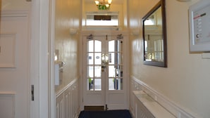 A hallway with a double door, a light fixture above, and a thermostat on the wall. - The Lindum (Hastings)