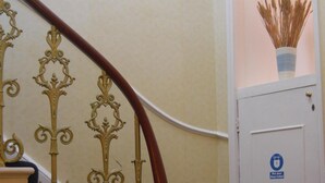 A staircase with ornate metal railings and a blue carpeted landing. - The Lindum (Hastings)