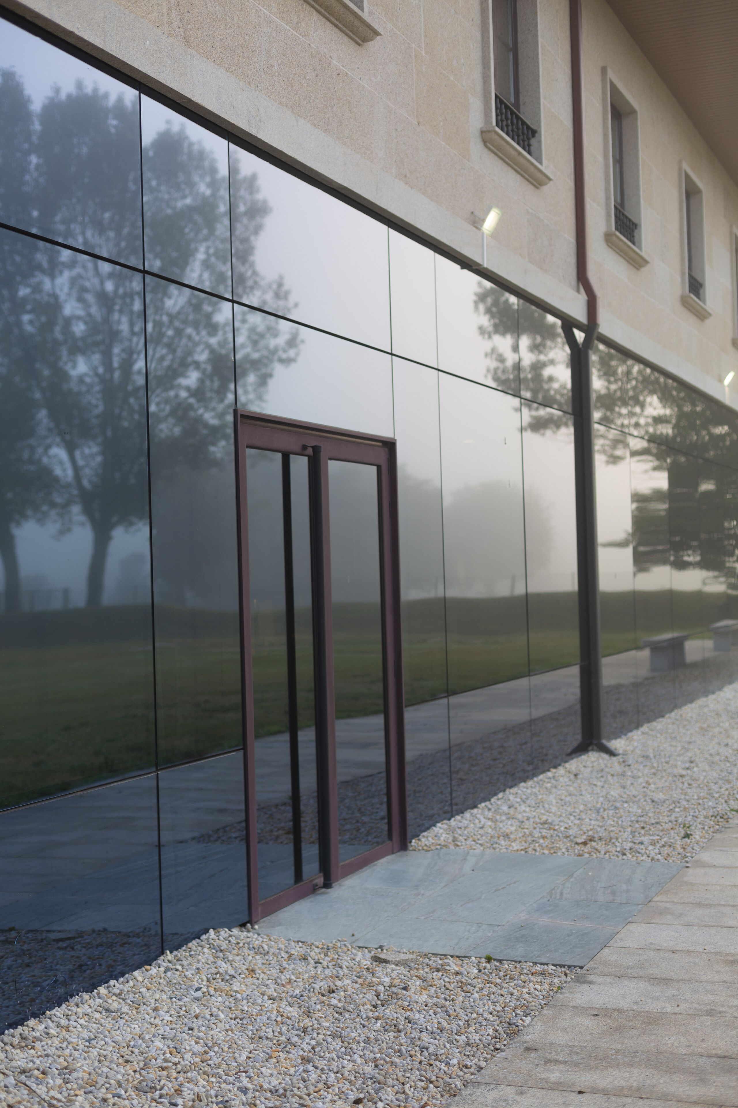 A modern building facade with reflective glass windows and a metal door frame.