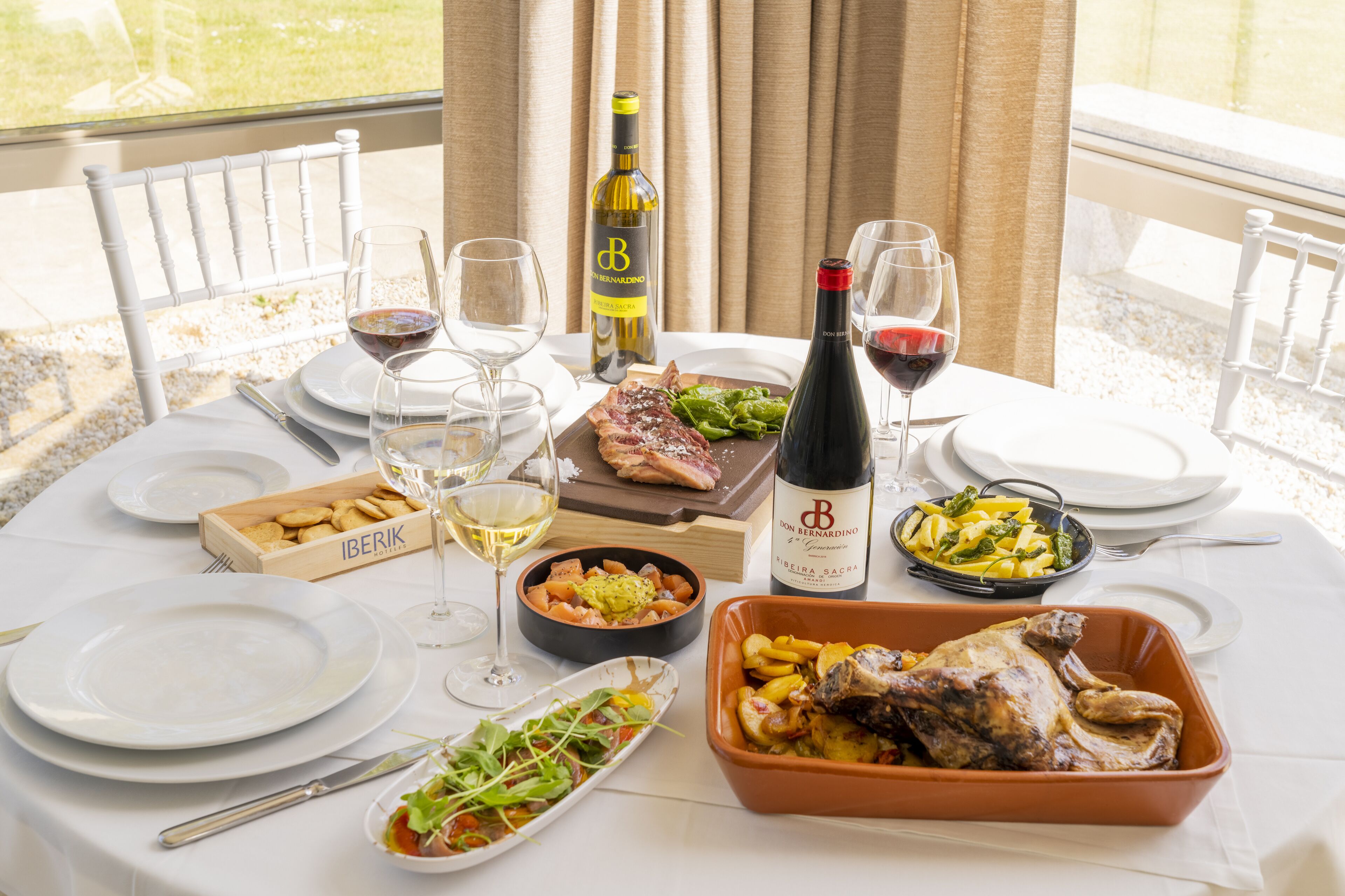Une table à manger dressée avec des assiettes, des verres, une bouteille de vin et divers plats.