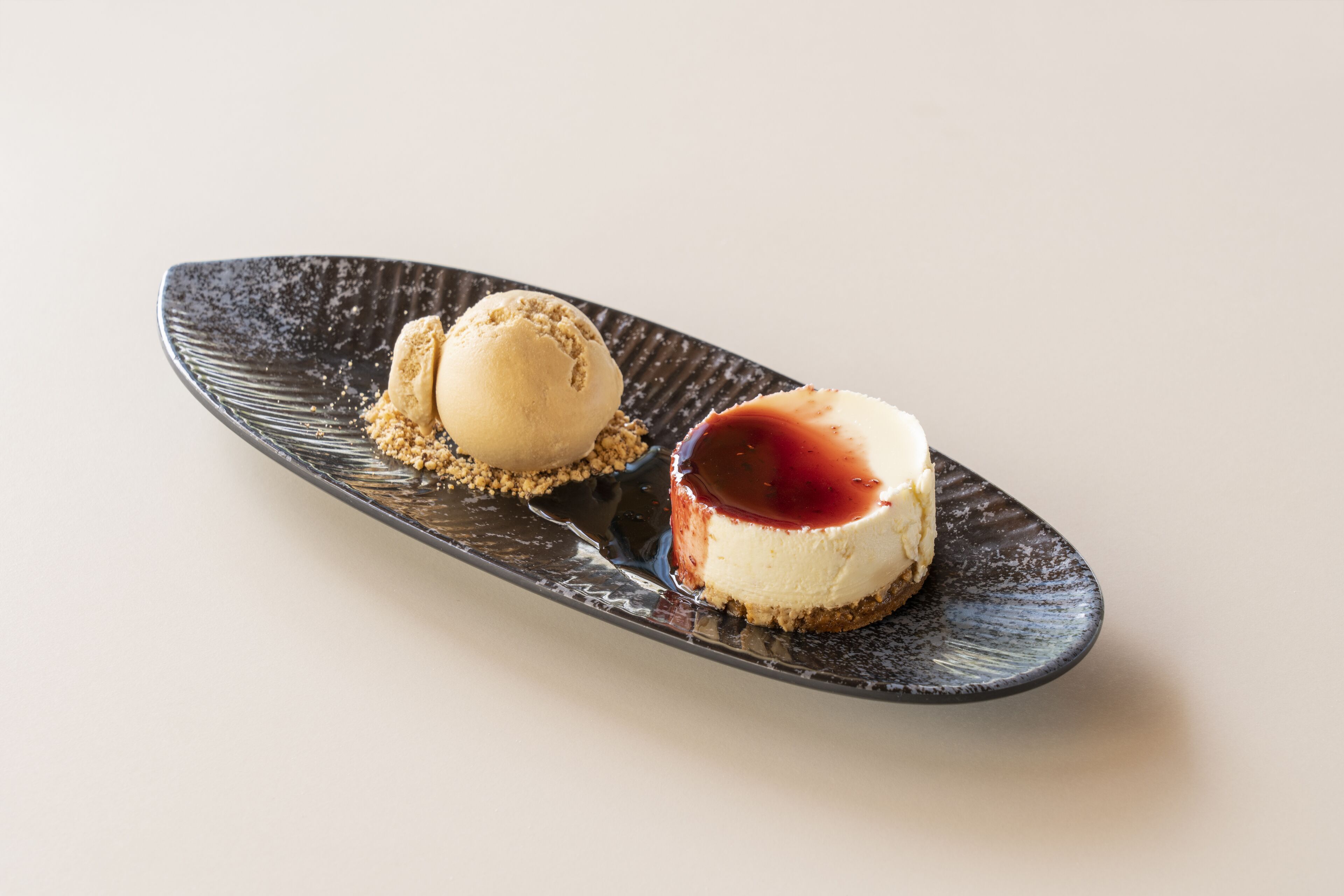 Ein Dessert auf einem dunklen Teller mit glatter Oberfläche.