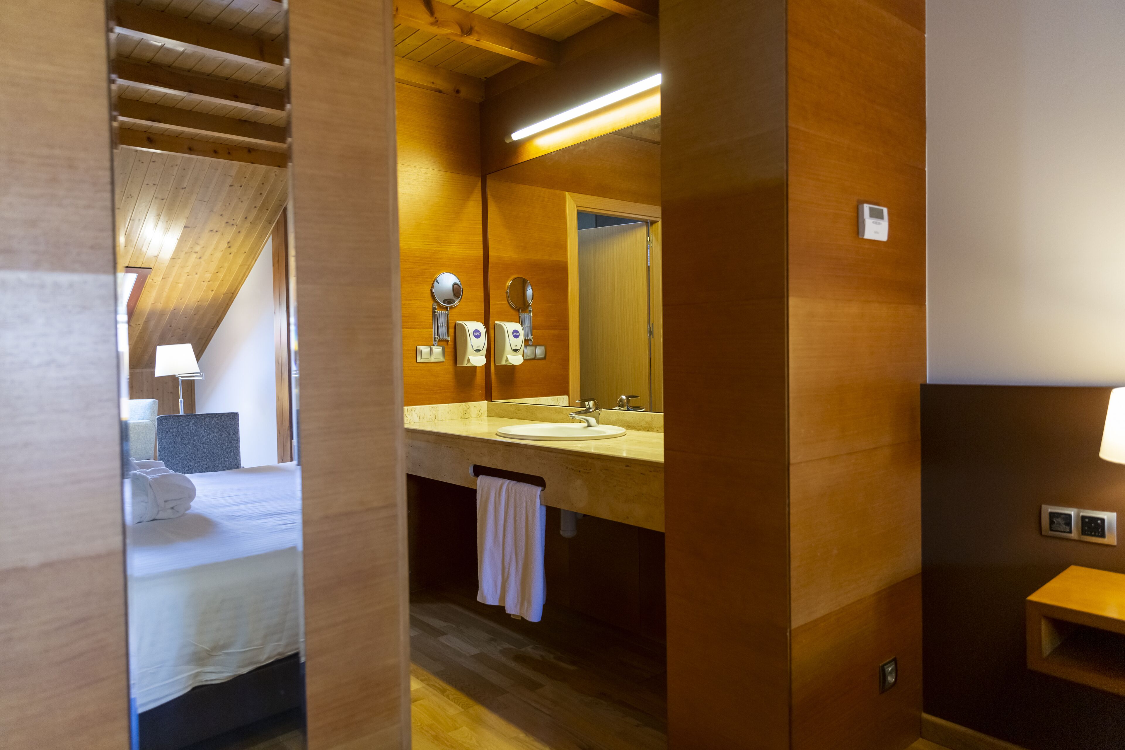 Une salle de bain moderne avec un plafond en bois, un lavabo, un miroir et une serviette accrochée au mur.