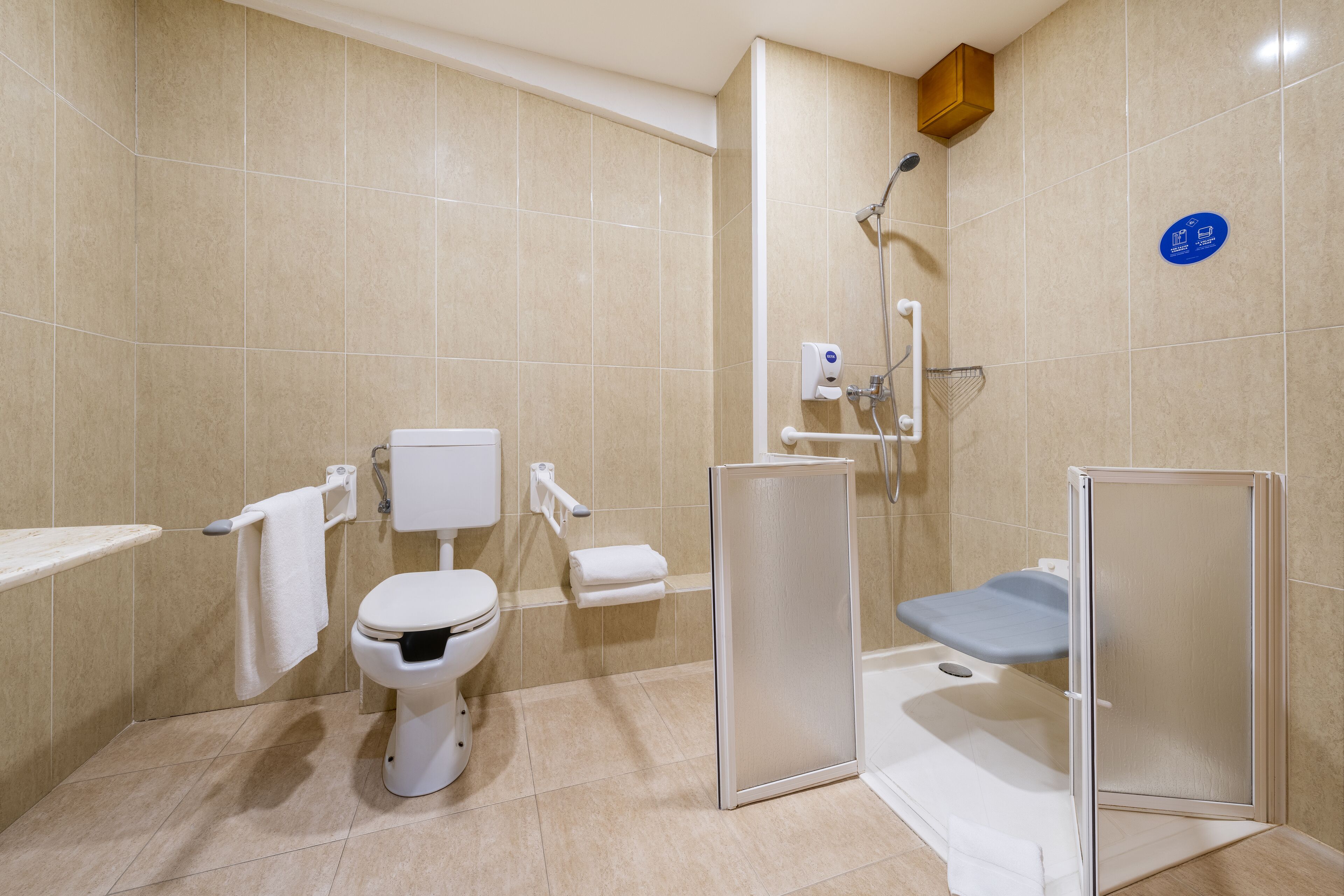 Un baño moderno con inodoro, ducha y un inodoro adicional para accesibilidad.
