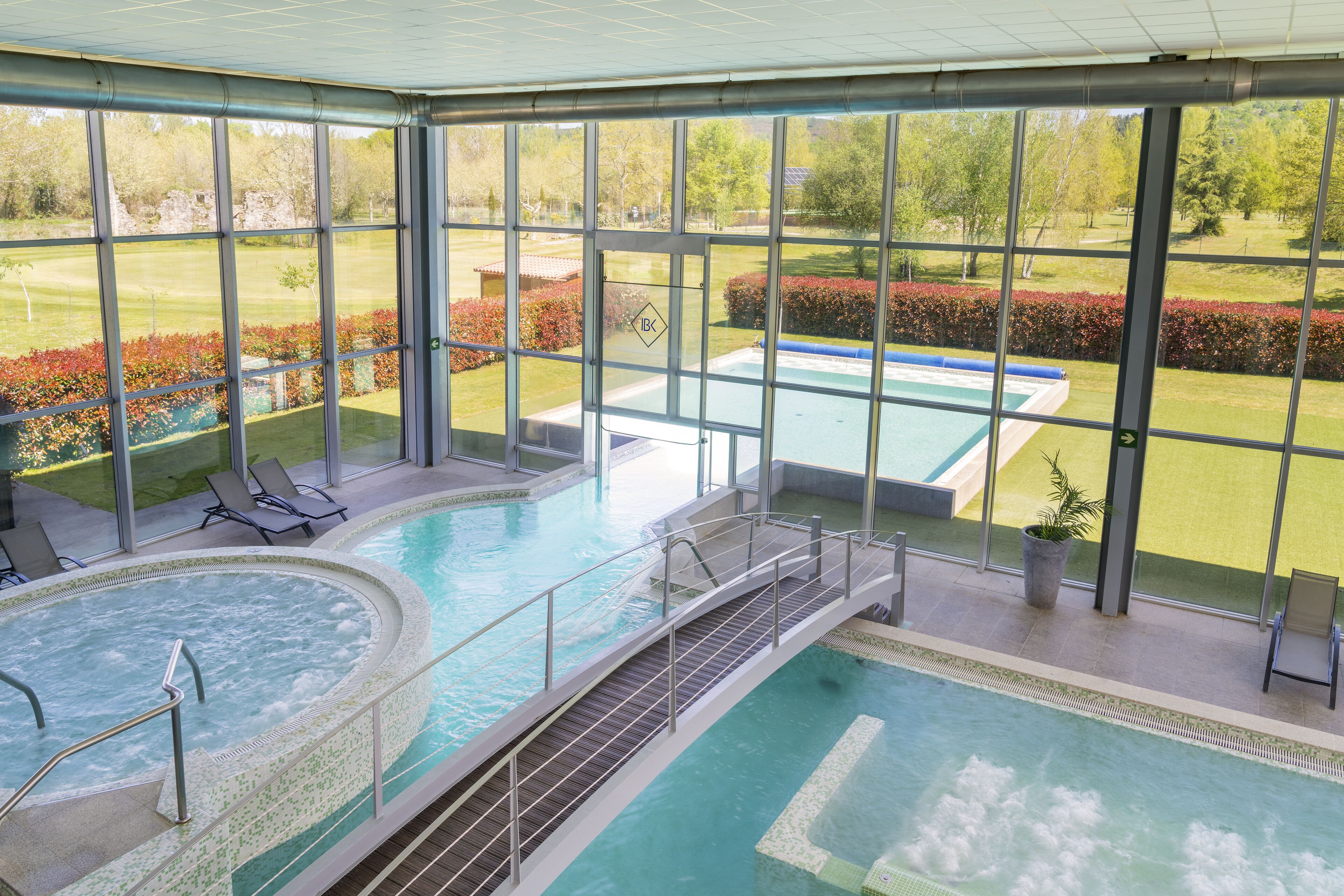 Una amplia piscina cubierta con vistas a un campo de golf y jardines cuidados.