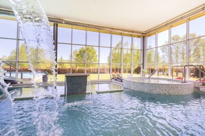 An indoor swimming pool with clear glass walls, a water feature, and a view of the outdoors. - Iberik Hotel Balneario Augas Santas (Panton)
