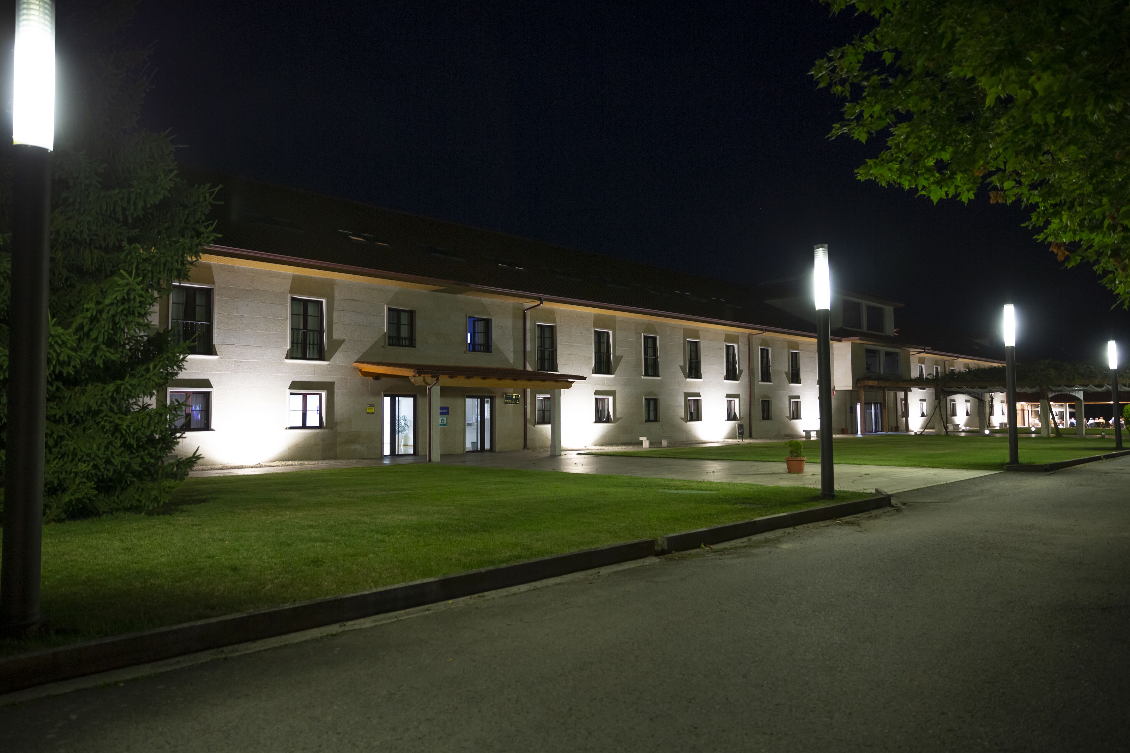 Un hotel con una hilera de habitaciones, un césped bien cuidado y farolas.
