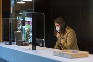A reception desk with a computer, a glass display case, and a plant in the background. - Iberik Hotel Balneario Augas Santas (Panton)