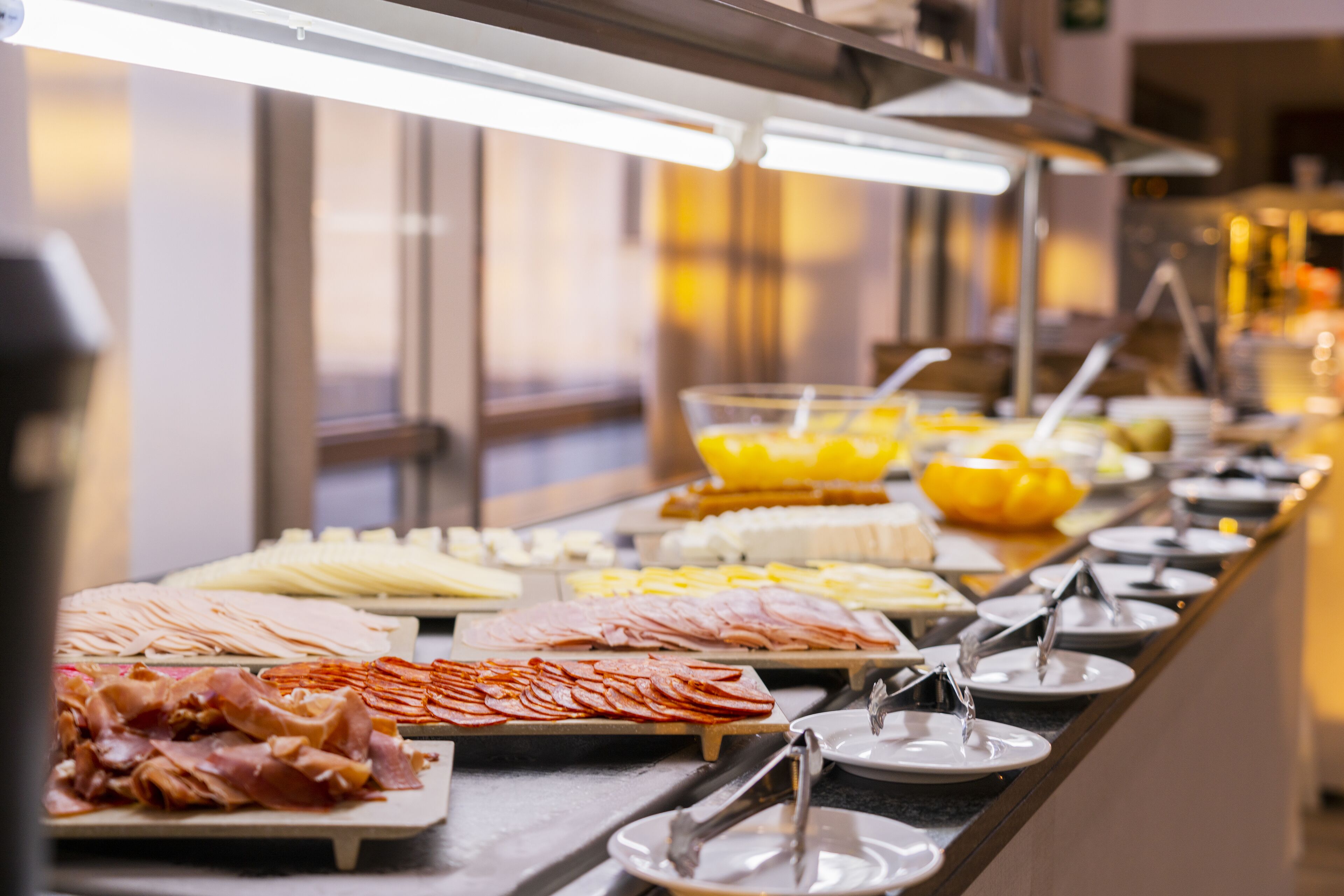 A buffet with various food items including meats, cheeses, and fruits.