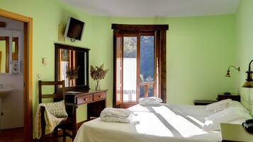 A bedroom with a bed, a desk, a chair, a television, and a window with a view.
